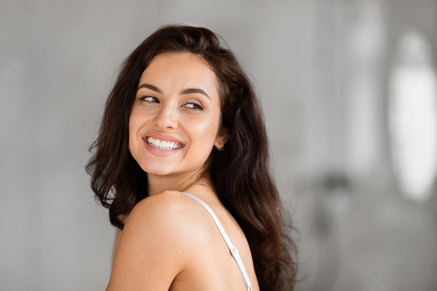 Young microneedling model with long brown hair and blue eyes.