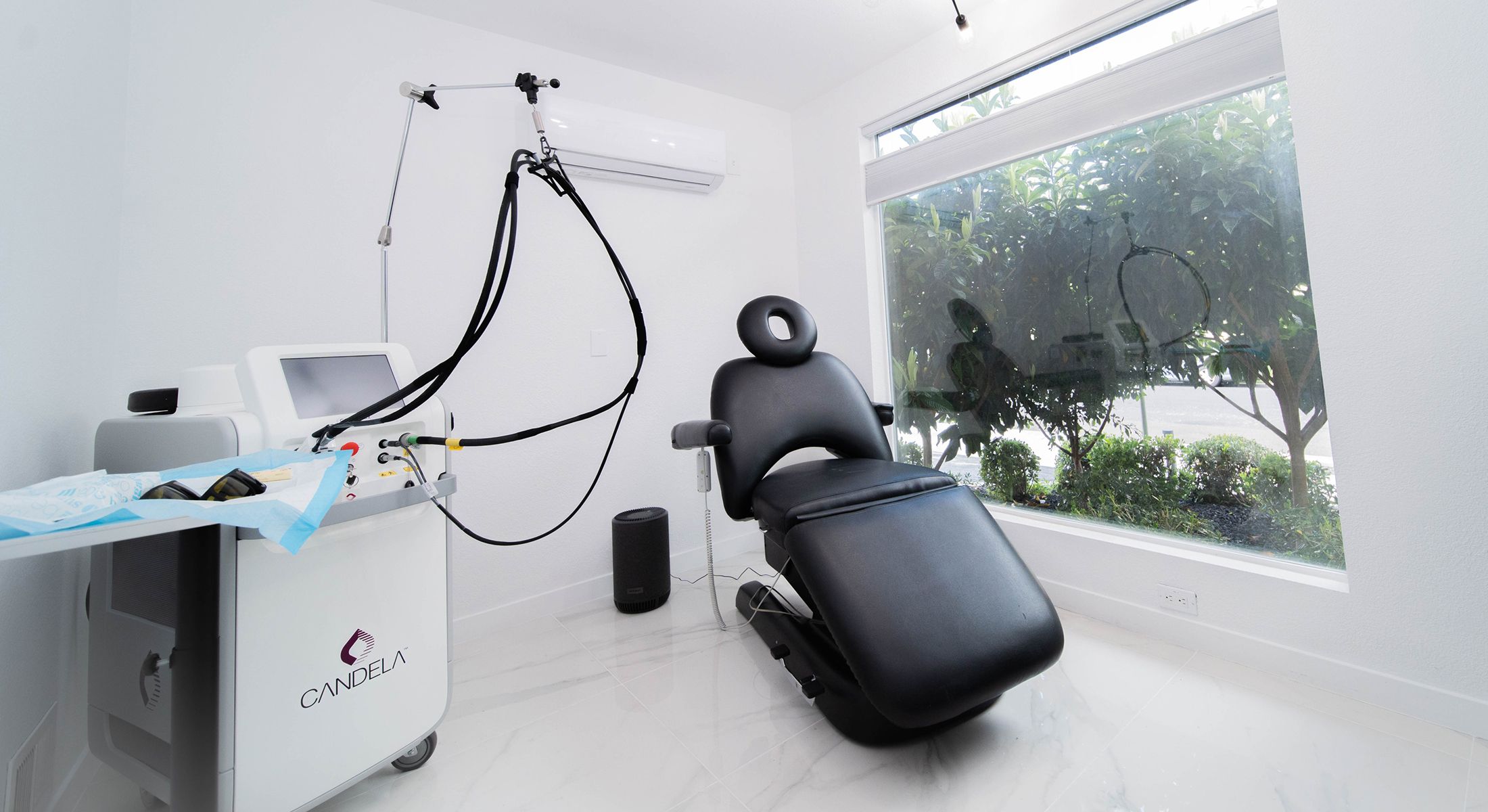 Laser treatment room with black chair and equipment.